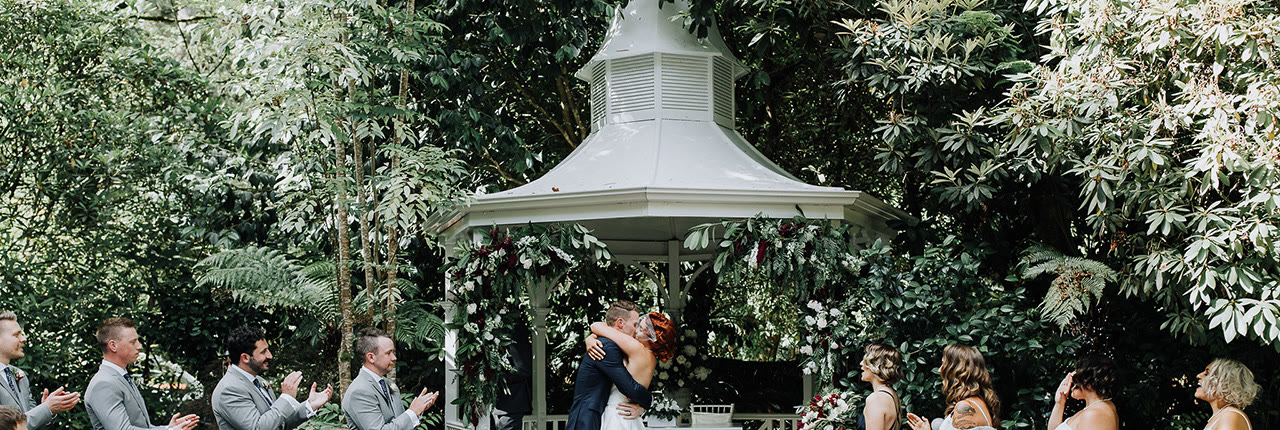 A kiss at the gazebo while the wedding party applauds.